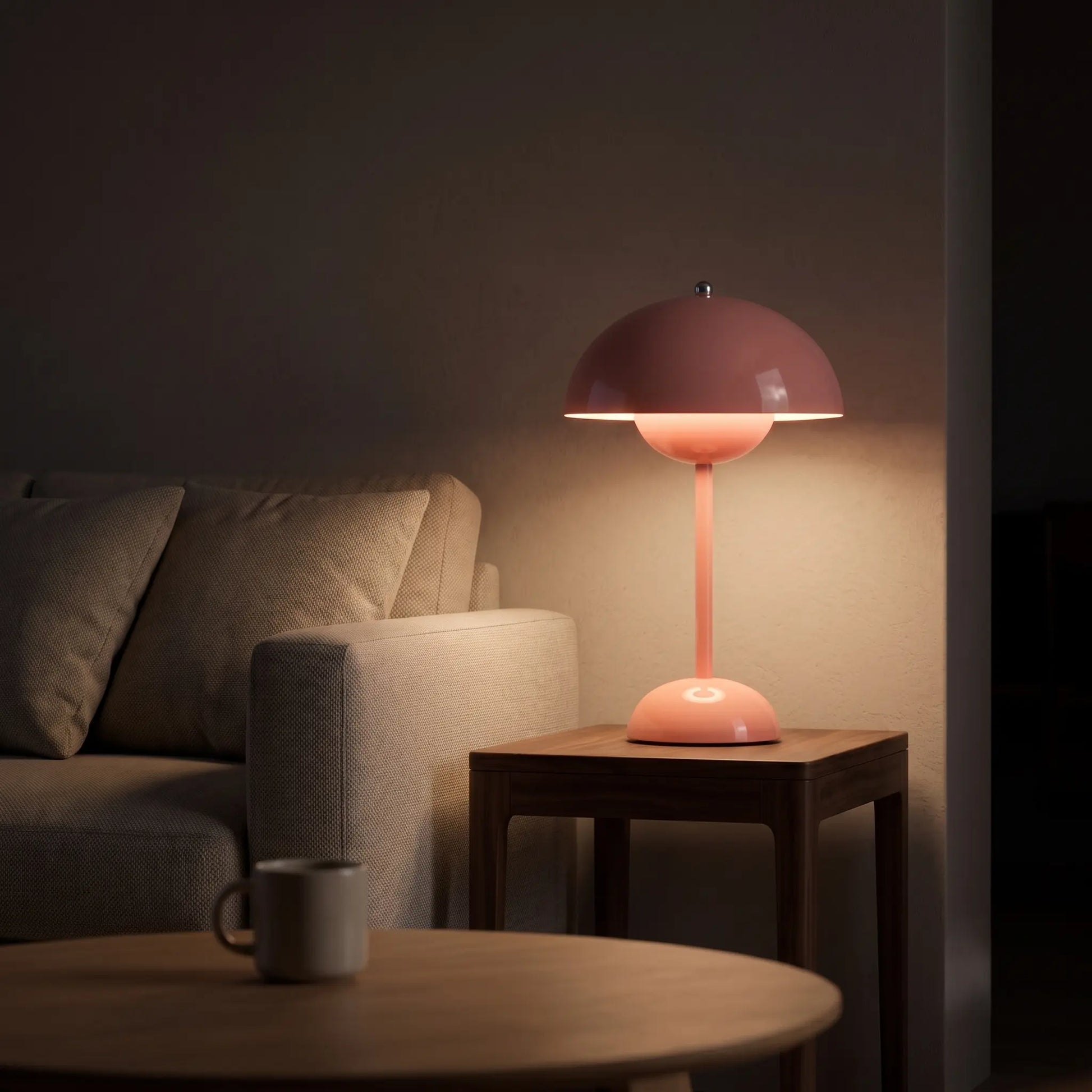 Aesthix Lume Bud pink retro table lamp glowing on a wooden side table in a cosy living room