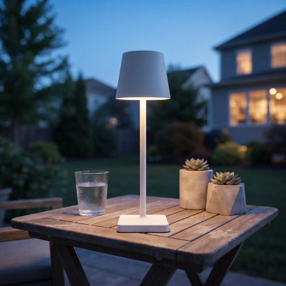 Aesthix Lume Classic white bar style touch table lamp glowing on an outdoor patio table 