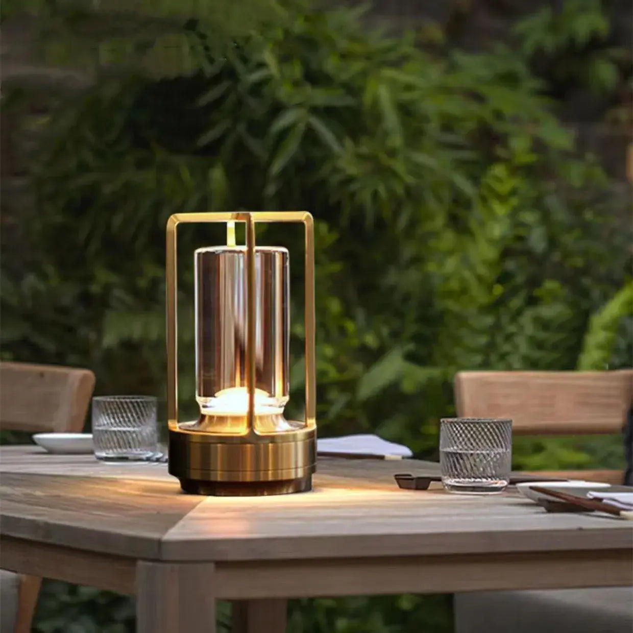 Aesthix Lume Luxe gold glass lantern table lamp on a wooden crate in an outdoor patio setting