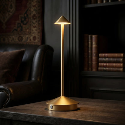 Aesthix Lume Vela slim rechargeable lamp glowing in a dark study with leather armchair and books
