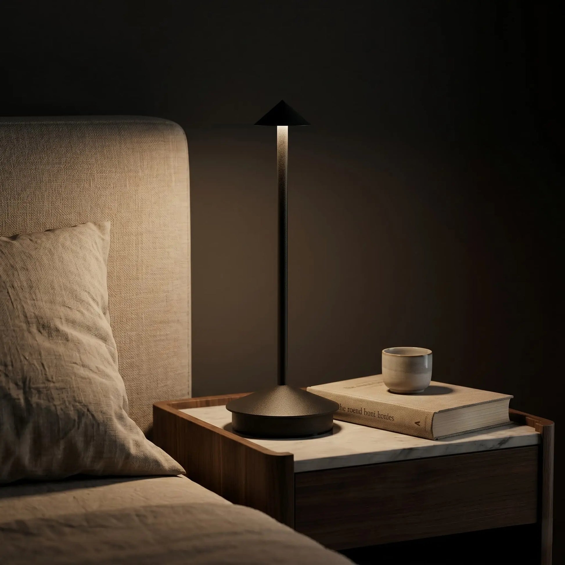 Aesthix Lume Vela slim rechargeable lamp glowing on a bedside table in a cosy dark bedroom