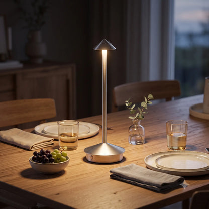 Aesthix Lume Vela slim rechargeable lamp on a dining table with plates and cups near a window